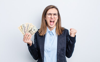 young pretty woman shouting aggressively with an angry expression. dollar banknotes concept