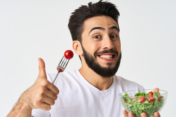 Cheerful man in a white T-shirt with a plate of light green and a healthy meal