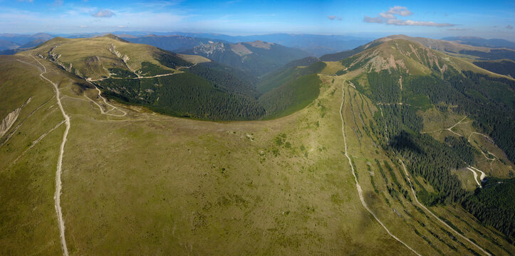 Aerial Drone panorama with a valley splitting to Nedeia and Balota Peak and the alpine pastures and forests surrounding them. Capatanii Massif, Carpathians, Romania
