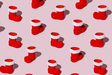 Christmas pattern with Santa Claus boots on pastel pink background. Getting ready for the New Year. Creative Holiday season concept. Minimal winter holidays texture art. Flat lay.