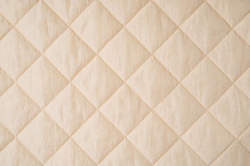 Quilted fabric background. Beige  texture blanket or puffer jacket
