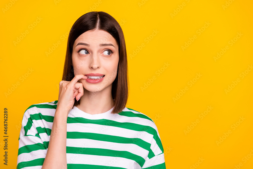 Wall mural Photo of stressed brunette young lady look empty space wear green t-shirt isolated on yellow color background