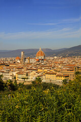 Naklejka premium Santa Maria del Fiore cathedral in Florence, Italy. Aerial panoramic view with dome by Filippo Brunelleschi, and bell tower dominating the skyline in Tuscany, Italy. Mountains and blue sky background.