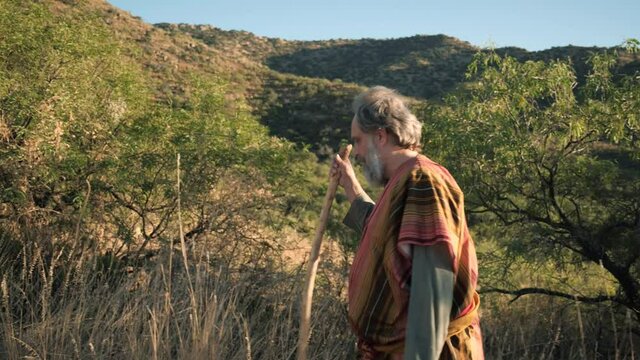 Side tracking a Bible prophet or holy man walking in the desert