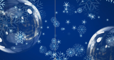 Image of snowflakes falling and christmas baubles on blue background