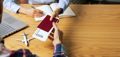 customer buying flight tickets in travel agency for his next trip - obrazy, fototapety, plakaty