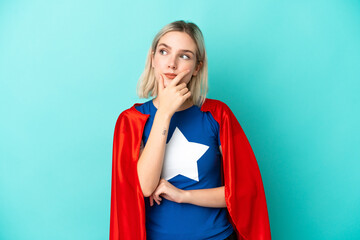 Super Hero caucasian woman isolated on blue background having doubts and with confuse face...