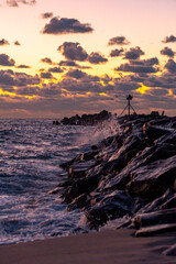 Waves crashing against the stone pier just before Sunrise