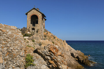 Fototapeta na wymiar Exterior of the Chapel, place of prayer located on a rocky cliff overlooking the sea, Alassio, Savona, Liguria, Italy 