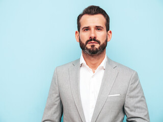Portrait of handsome confident stylish hipster lambersexual model.Sexy modern man dressed in elegant suit. Fashion male posing in studio near blue wall