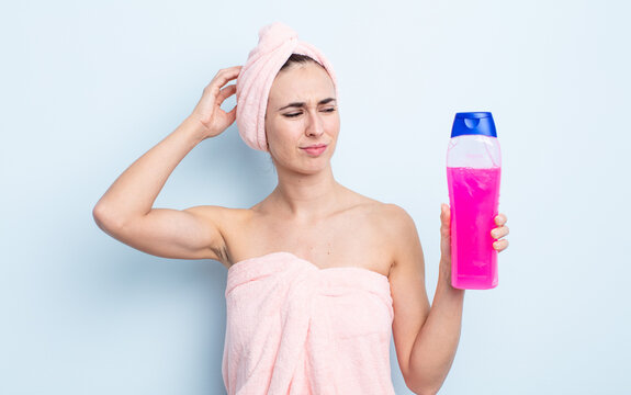 young pretty woman feeling puzzled and confused, scratching head. shower and shapoo concept