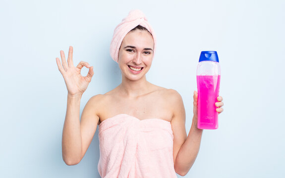 young pretty woman feeling happy, showing approval with okay gesture. shower and shapoo concept