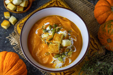 Autumn vegetarian pumpkin and carrot soup with cream, croutons and seeds. Comfort food, autumn and winter healthy slow food concept