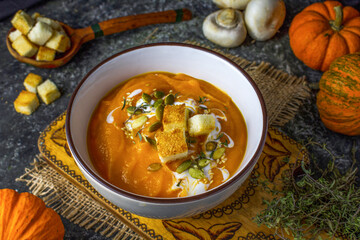 Autumn vegetarian pumpkin and carrot soup with cream, croutons and seeds. Comfort food, autumn and winter healthy slow food concept