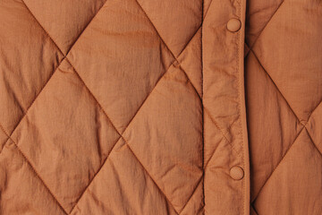 Close-up on brown puffer jacket texture. Quilted fabric background