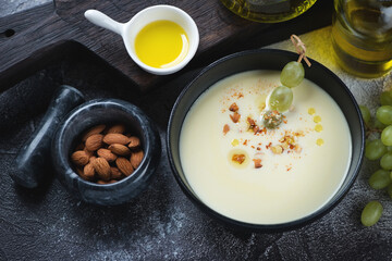 Bowl of ajoblanco or spanish traditional cold soup, elevated view on a dark-grey stone background,...