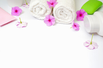 Spa white background pink flowers and a bottle of shampoo, soap and cream lotion. White towel rolls. Copy space in the center, empty space for text