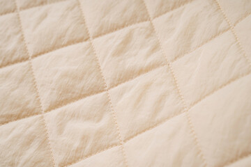 Quilted fabric background. Beige  texture blanket or puffer jacket