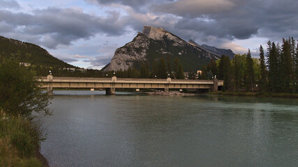 View of stream with Bow River Bridge in the town of Banff, Alberta, Canada in the Rocky Mountains with majestic Mount Rundle in background.