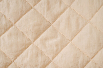 Quilted fabric background. Beige  texture blanket or puffer jacket