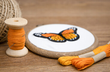 Background with fabric in an embroidery frame and threads.A spool of orange threads. The process of...