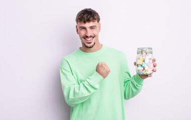 young handsome man feeling happy and facing a challenge or celebrating. jelly candies concept