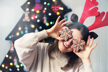 Christmas woman portrait. Cheerful funny girl cover her eyes with x-mas gingerbread snowflake...