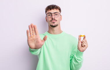 young handsome man looking serious showing open palm making stop gesture. contact lenses