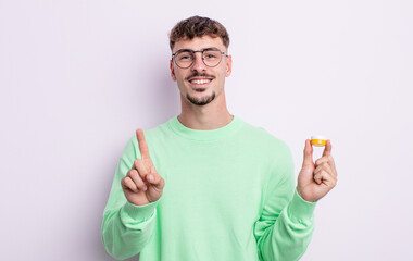 young handsome man smiling and looking friendly, showing number one. contact lenses
