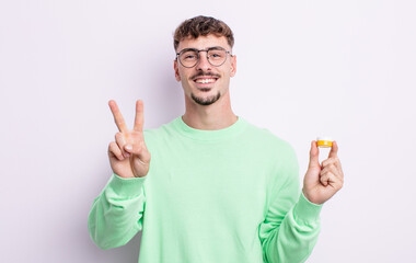 young handsome man smiling and looking friendly, showing number two. contact lenses