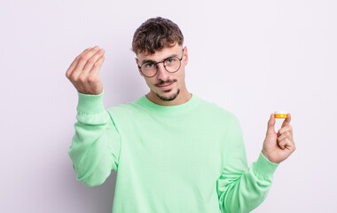 young handsome man making capice or money gesture, telling you to pay. contact lenses