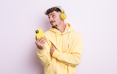 young handsome man shrugging, feeling confused and uncertain. music concept