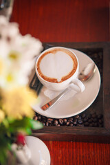 white cup of cappuccino on a red table in a cafe