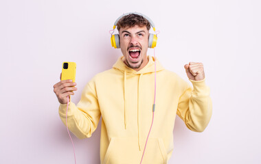 young handsome man shouting aggressively with an angry expression. music concept