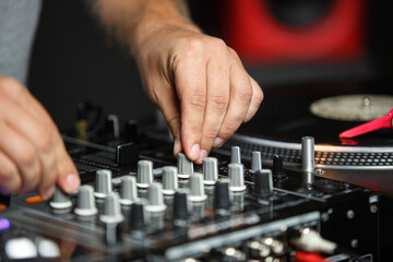 Hands of dj playing music in night club on party