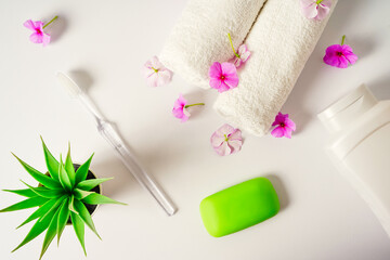 Obraz na płótnie Canvas Spa white background pink flowers and a bottle of shampoo, soap white towels rolls. Body care, hygiene and cleanliness concept