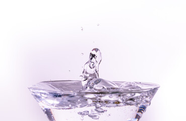 Close-up of water drop falling into a glass on white background