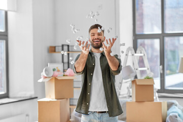 moving, people and real estate concept - happy smiling man with foam peanut having fun at new home