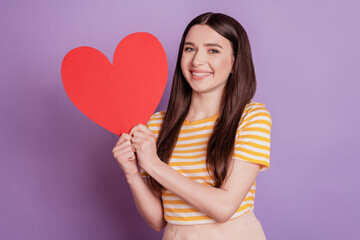 Portrait of adorable sweet lady showing big red paper heart white smile on purple background