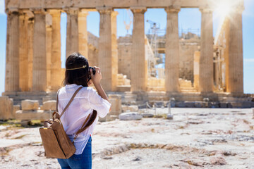 A female tourist is taking photos of the Parthenon Temple at the Acropolis of Athens, Greece,...