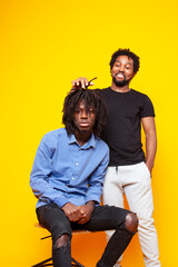 Obraz premium two african american guys posing cheerful together on yellow background, lifestyle people concept