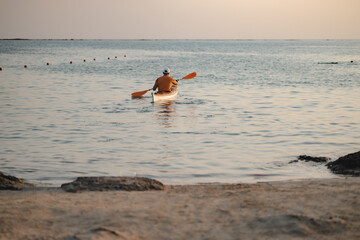 Man swimming in the kayak off the shore of the beach