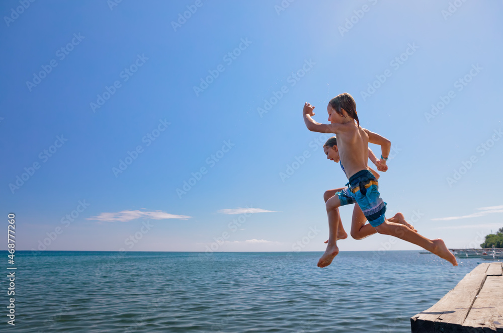 Wall mural young happy couple have fun at sea beach. children run, jump high into water. popular travel destina