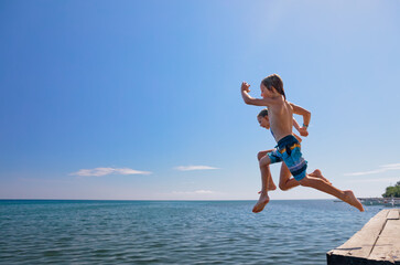 Young happy couple have fun at sea beach. Children run, jump high into water. Popular travel...