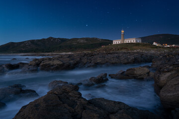 Lighthouse at night with starry sky. Canota, Galicia, Spain