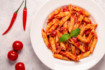 Classic italian pasta penne alla arrabiata with fresh basil on a light background