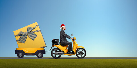 Santa Claus in suit on yellow scooter with red gift box