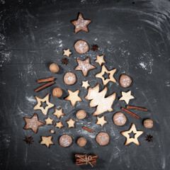 Fototapeta na wymiar Homemade cookies, cinnamon, walnuts, anise stars laid out as Christmas tree on black.