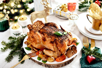 Roasted whole chicken with vegetables and garlic on Christmas table