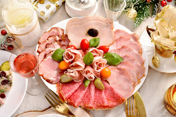 Festive table with a platter of sliced ham and cured meats for Christmas Top view